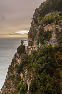Scenic view of sea by cliff against sky