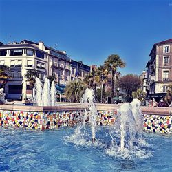 People in swimming pool against buildings in city