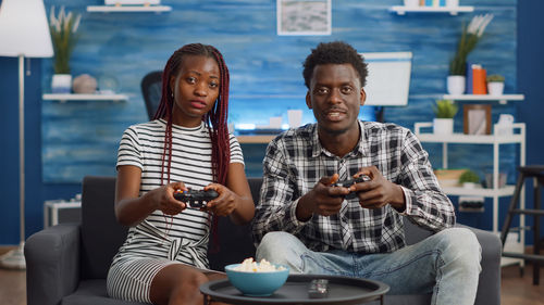 Young couple playing game while sitting at home