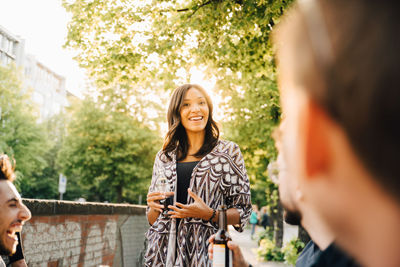 Young female with drink standing while looking at friends in social gathering