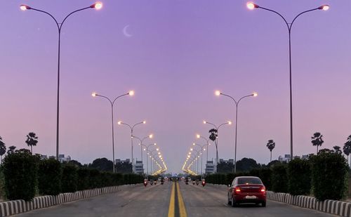 Cars on road against sky at dusk