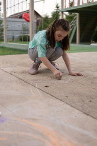 Girl draws with colorful crayons on pavement. children's drawings with chalk on wall. creative 