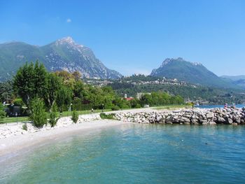 Scenic view of sea and mountains against clear blue sky