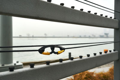 Low angle view of railing against sky with 2 coupled carabiners in foreground 