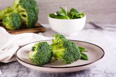 Fresh broccoli divided into inflorescences on a plate on the table. vegetable diet.