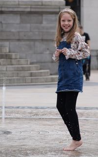 Portrait of smiling girl playing in fountain on street