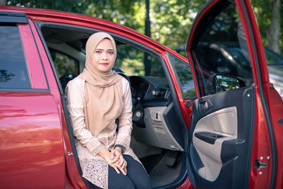 Woman standing by red car