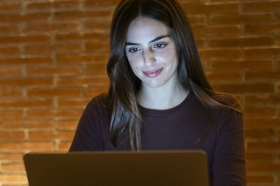 Young woman using laptop while sitting on table