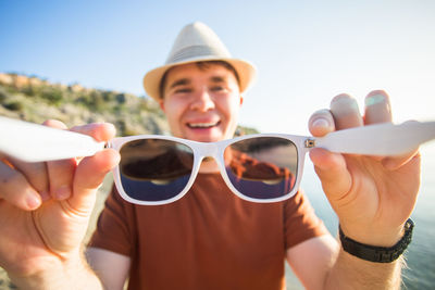 Portrait of happy man wearing sunglasses against sky