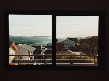 Close-up of cityscape against sky seen through window