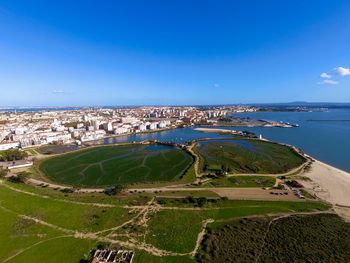 High angle view of sea and cityscape against blue sky