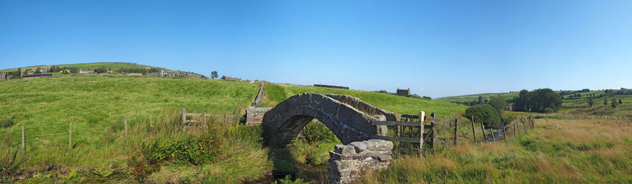 Ancient stone packhorse bridge over a stream in west yorkshire countryside near colden