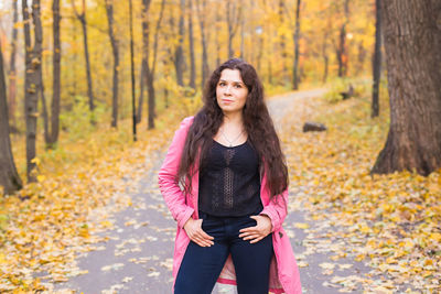 Portrait of teenage girl standing in forest during autumn