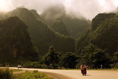 People traveling on motorcycle against mountains
