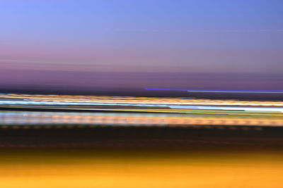 Blurred motion of light trails in sea against sky at sunset