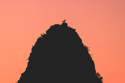 Silhouette rock formation against orange sky