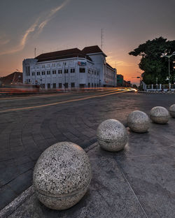 Street by buildings against sky at sunset