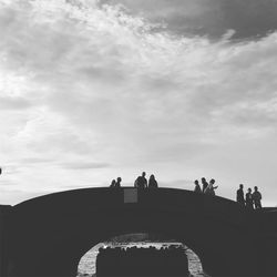 Silhouette people standing on bridge against sky