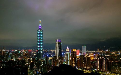 Illuminated buildings in city against sky at night