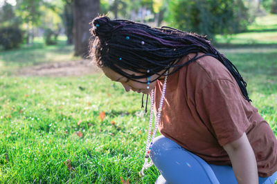 Young european woman is sitting on a grass and doing yoga exercise. healthy lifestyle outdoors.