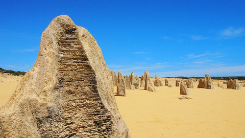 Panoramic view of sand dune in desert against blue sky