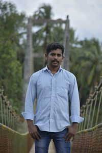 Portrait of young man standing against railing