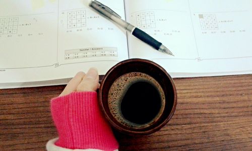 Close-up of hand holding coffee cup on table