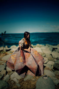 Rear view of woman sitting on beach