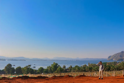 Man standing on land against clear blue sky