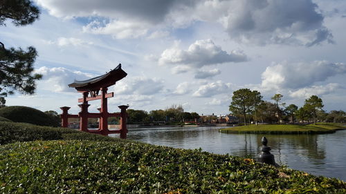 Torii gate in lake against cloudy sky