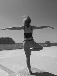 Rear view of woman standing by sea against clear sky