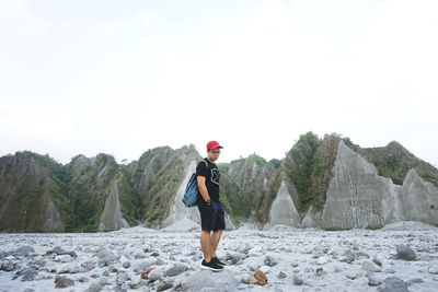 Young man standing on rocky beach