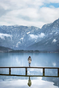 Woman standing on bridge over lake against mountains