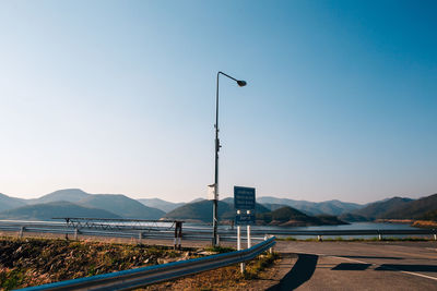 Street by lake against clear blue sky