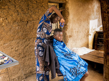 Man cutting hair of customer at barber shop in village