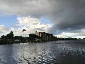 Buildings by river against sky