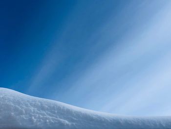 Low angle view of snowcapped mountains against clear blue sky