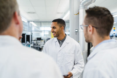 Team of competent electrical technicians in lab coats having meeting in electronics factory