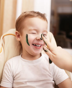 Cropped hand of woman painting boy face