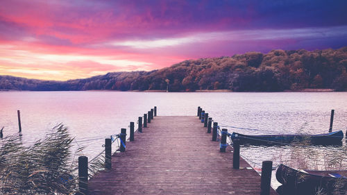 Pier over lake against sky during sunset