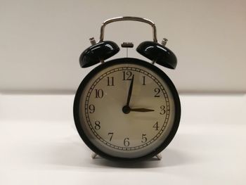 Close-up of alarm clock on white table