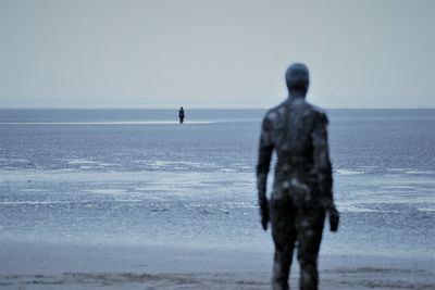 Statues on beach against sky