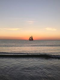 Sailboat sailing on sea against sky during sunset