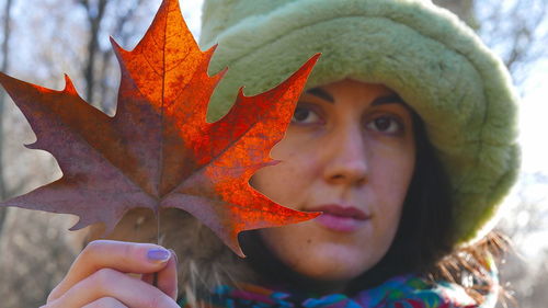 Close-up portrait of young woman with autumn leaves