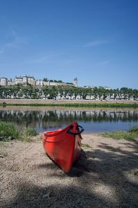 Red boat moored on river against buildings