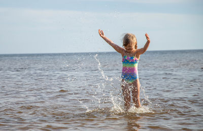 Rear view of shirtless boy playing in sea