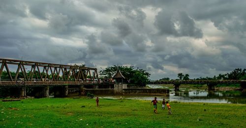 People standing on grass against cloudy sky