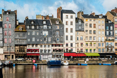 Buildings by canal against sky in city