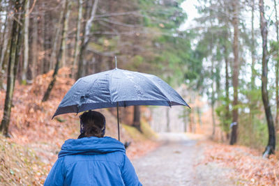 Rear view of woman with umbrella standing outdoors