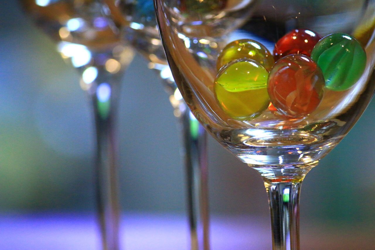 close-up, focus on foreground, glass - material, transparent, indoors, drinking glass, selective focus, water, freshness, drop, fragility, still life, glass, refreshment, reflection, table, drink, bubble, multi colored, no people